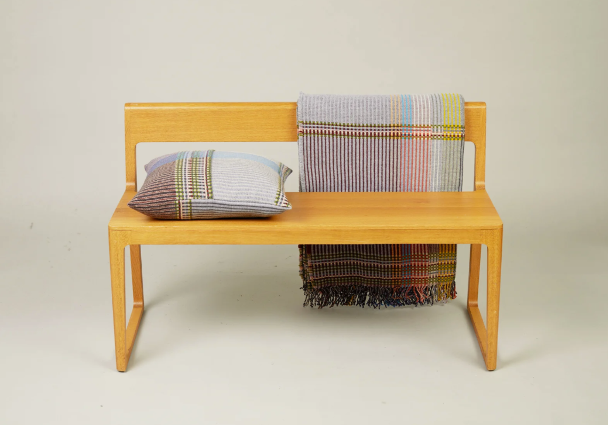 Wallace and Sewell plaid og pude på bænk. Hver en er unik da den er håndvævet. model Joan