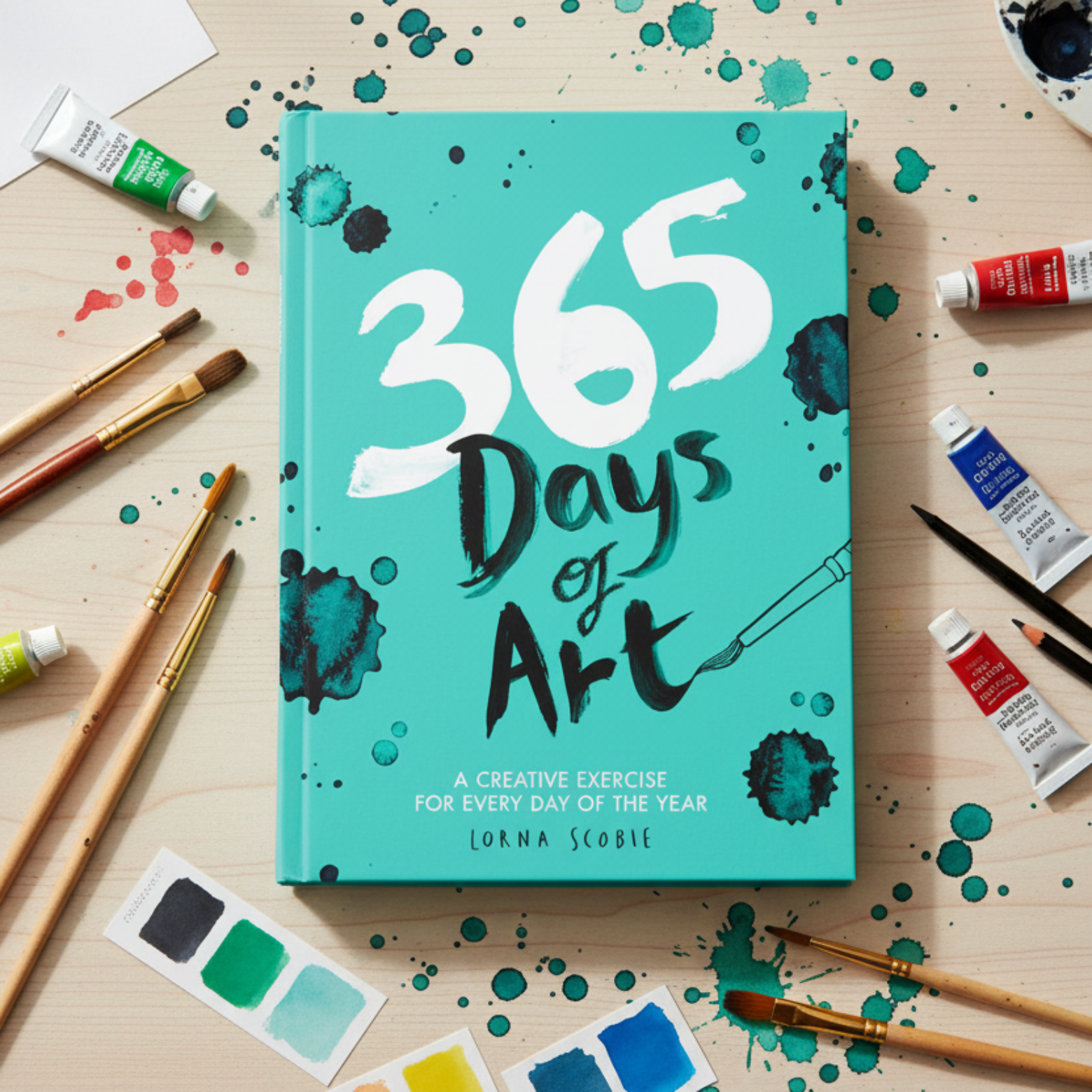Forside af 365 Days of Art dagbog med kreative øvelser. Bogen er vist på bordplade med pensler og akvarel. Forfatter Lorna Scobie.