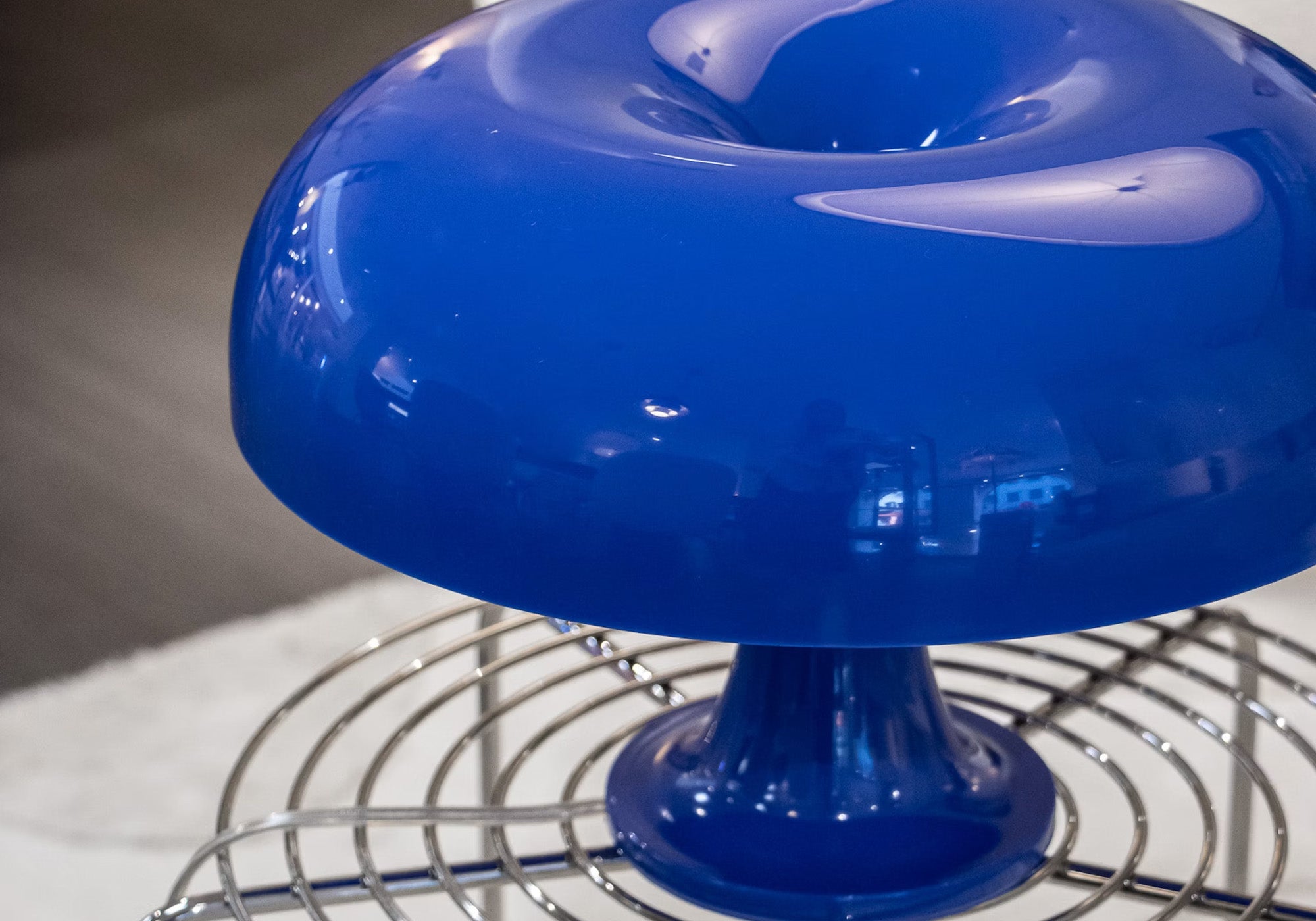 Bordlampe Nessino i mørkeblå fra det italienske designbrand Artemide stylet på stålbord.