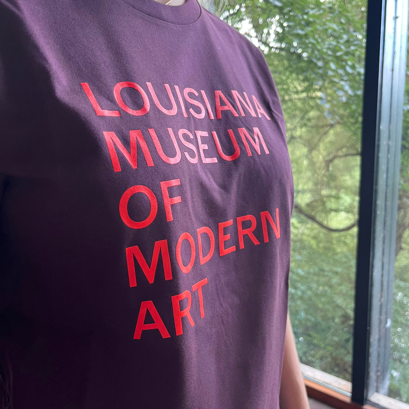 T-shirt i brun med teksten “Louisiana Museum of Modern Art” i orange print på Louisiana Museum of Modern Art.