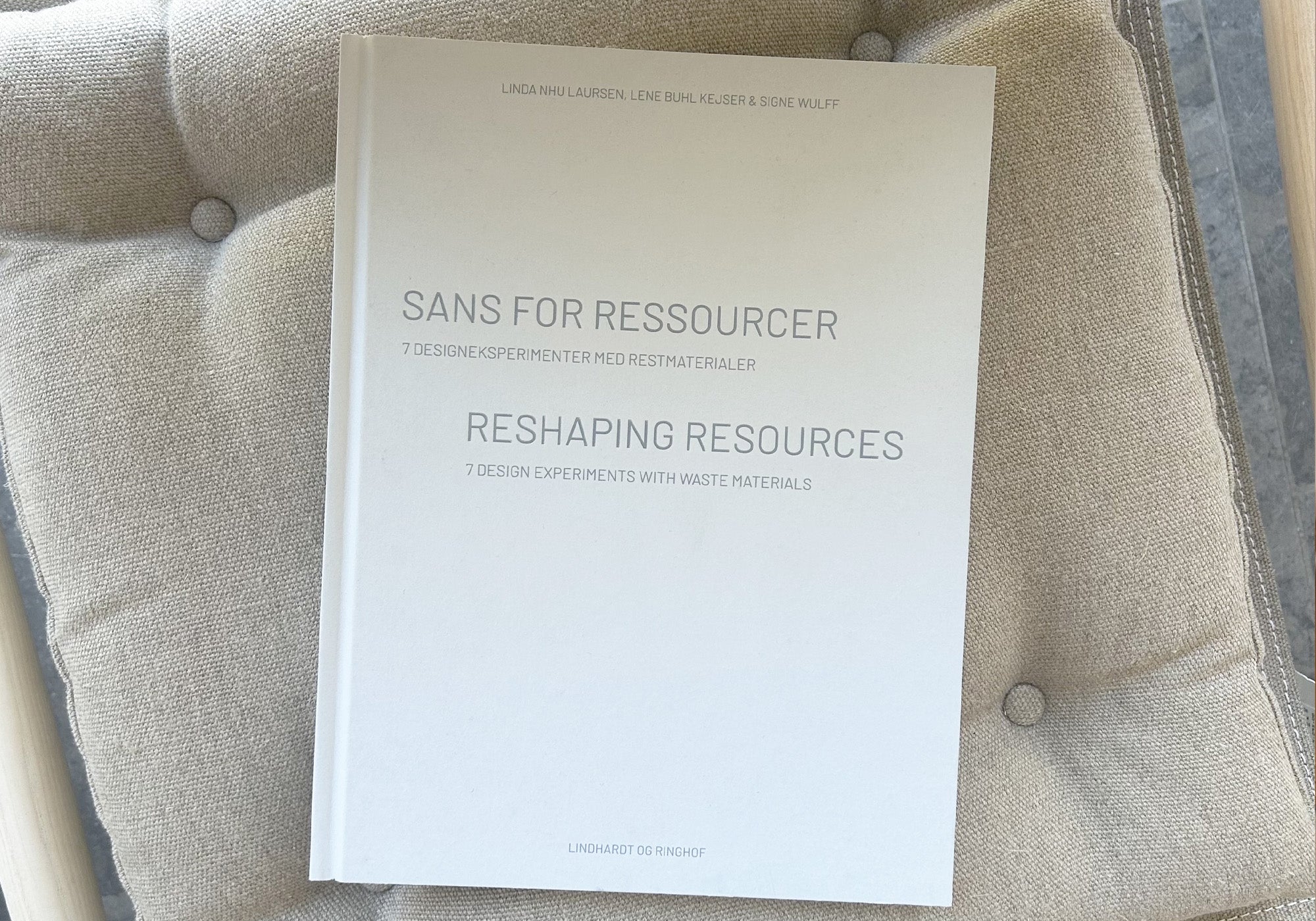 Forside af Sans for Ressourcer - syv designeksperimenter fra forskningsprojektet ’ReshapeWaste’ stylet på stol i Louisianas interiør. Louisiana Museum of Modern Art.